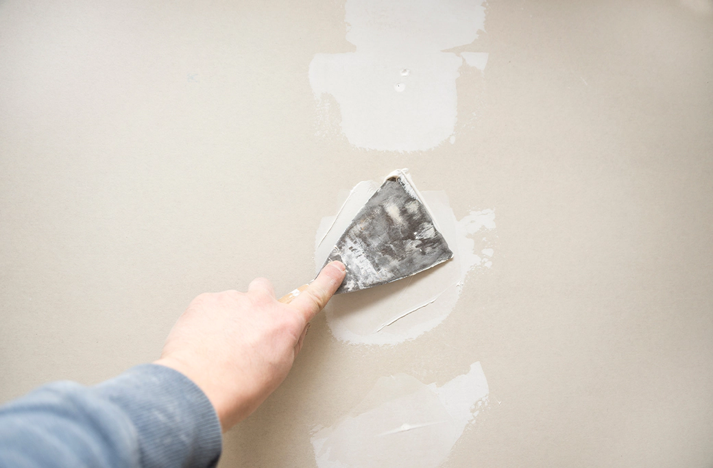 Painter inspecting wall repairs before estimating an interior painting project